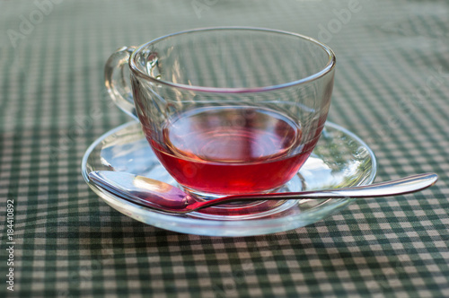 A cup of fruit tea on a checkered tablecloth.