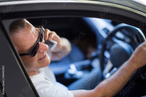 Smiling senior man talking on phone in car