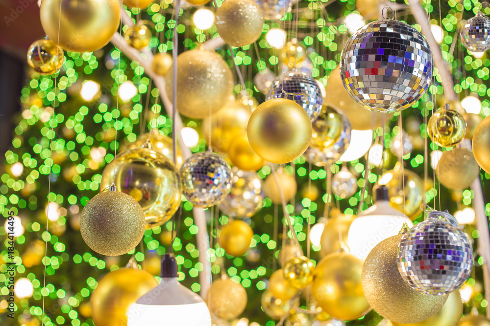 Golden Christmas ball hanging on Christmas tree with green bokeh in night time Golden Christmas ball hanging on Christmas tree with green bokeh in night time