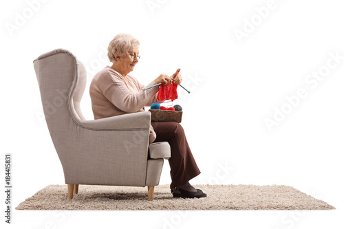 Senior lady sitting in an armchair and knitting