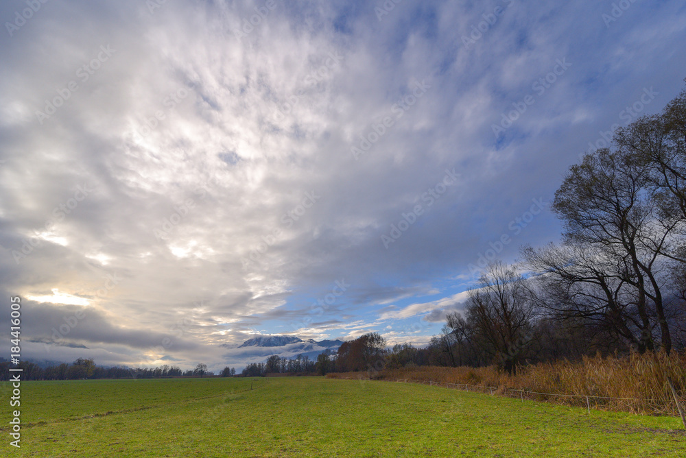 Naklejka premium Vista panoramica di campagna, con cielo azzurro e nuvole bianche e grigie