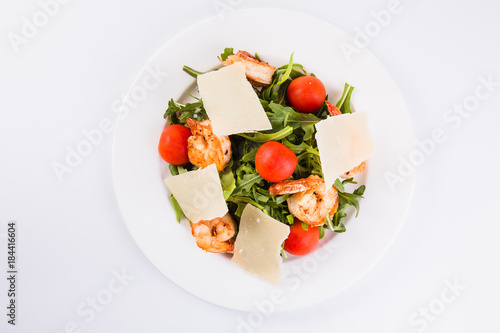 Fresh dietary salad with shrimps, ruccola, cherry tomatoes and Parmesan cheese. (Light background and close top view)