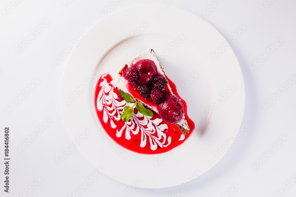 cheese cake with strawberries and raspberries on a white plate on a light background (close) cheese cake with strawberries and raspberries on a white plate on a light background (close)