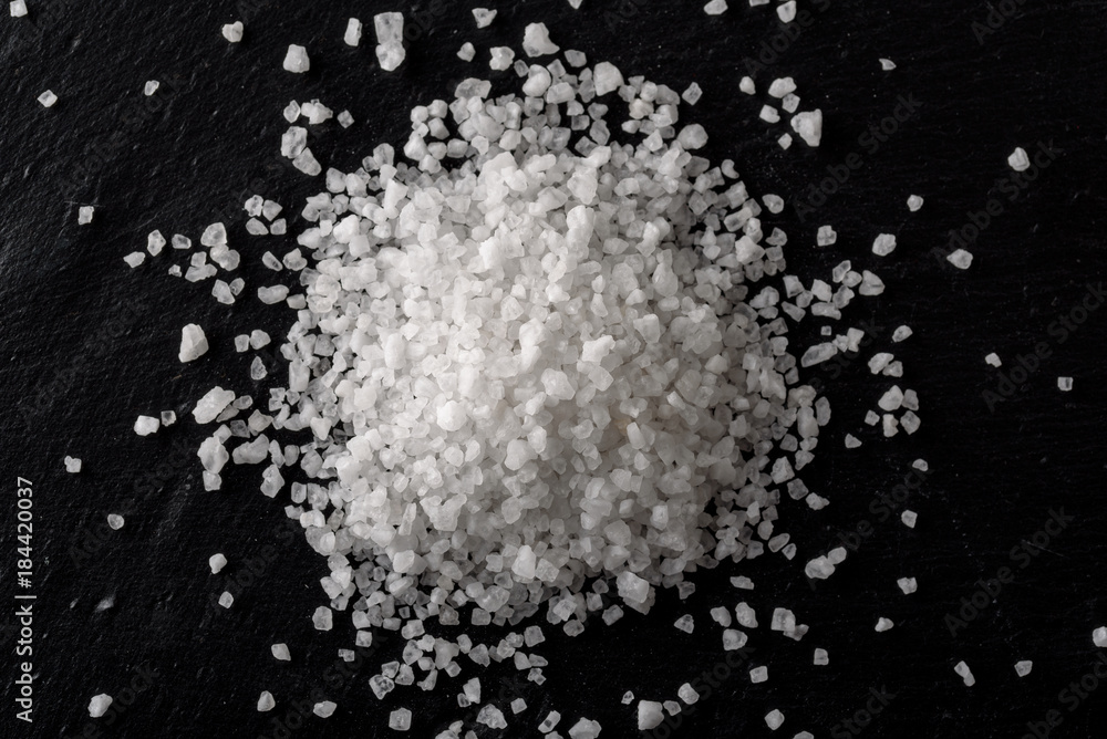 Sea white salt on black stone background Sea white salt on black stone background