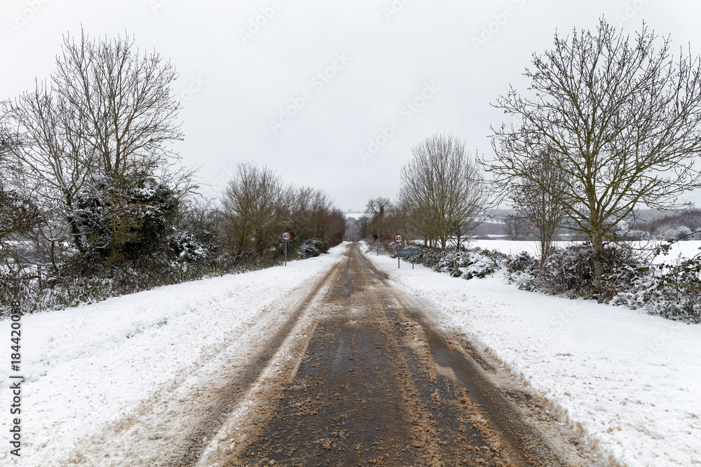 Snow covered road through winter countryside