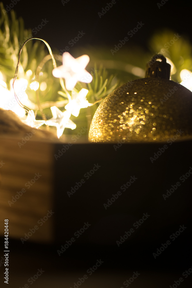 Christmas decoration in wooden platter with lights, garlands, golden baubles, spruce tree and cones. Toned.