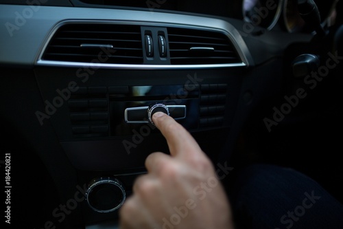 Cropped hand adjusting volume in car