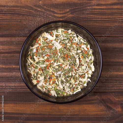Spice mix - celery, parsley, parsnip, leeks, onions, dill, basil, carrot in a bowl on a wooden background