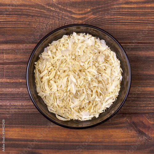Dried onion in a bowl on a wooden background
