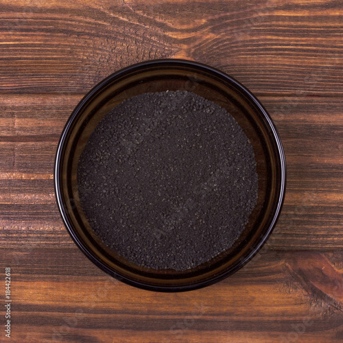 Black cumin powder in a bowl on a wooden background