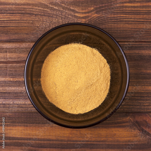 Cinnamon powder in a bowl on a wooden background