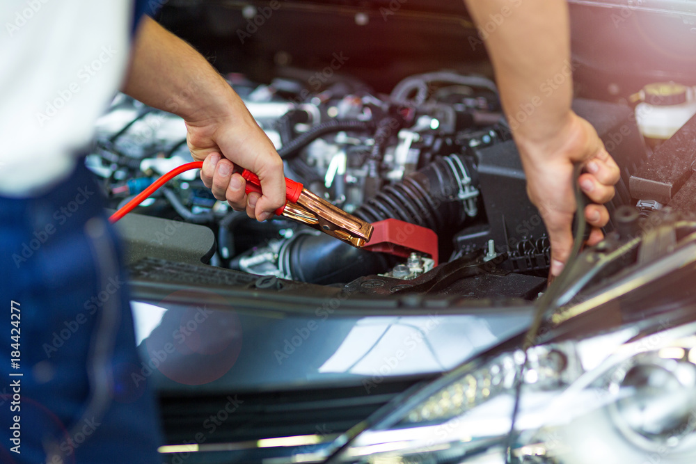 Mechanic using jumper cables to start a car
Mechanic using jumper cables to start a car