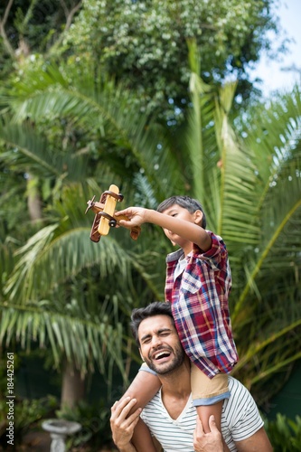 Happy father carrying son while standing in yard