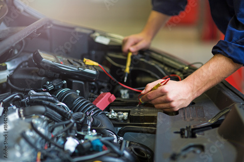Auto mechanic checking car battery voltage 