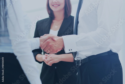 Happy business partners shaking hands in an office