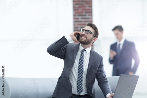 Confident young man talking on phone in office