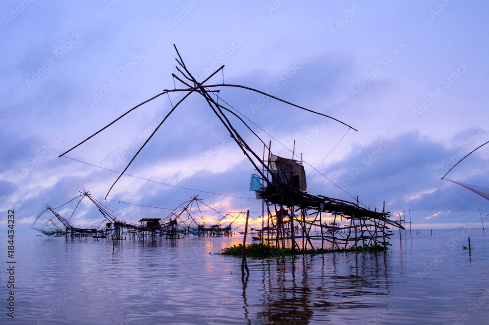 Beautiful landscape view sunrise at Pak Pra lake, Pattalung, Thailand with twilight sky background,silhouette of traditional fishing method using a bamboo square dip net.