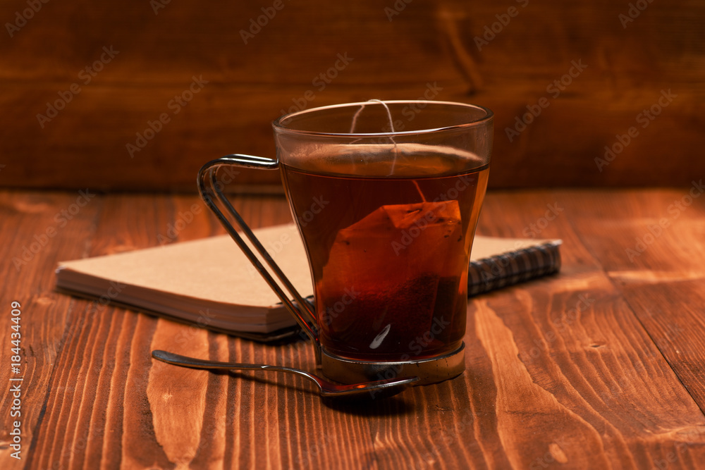 Tea and notebook on wooden background. Glass of black tea Tea and notebook on wooden background. Glass of black tea