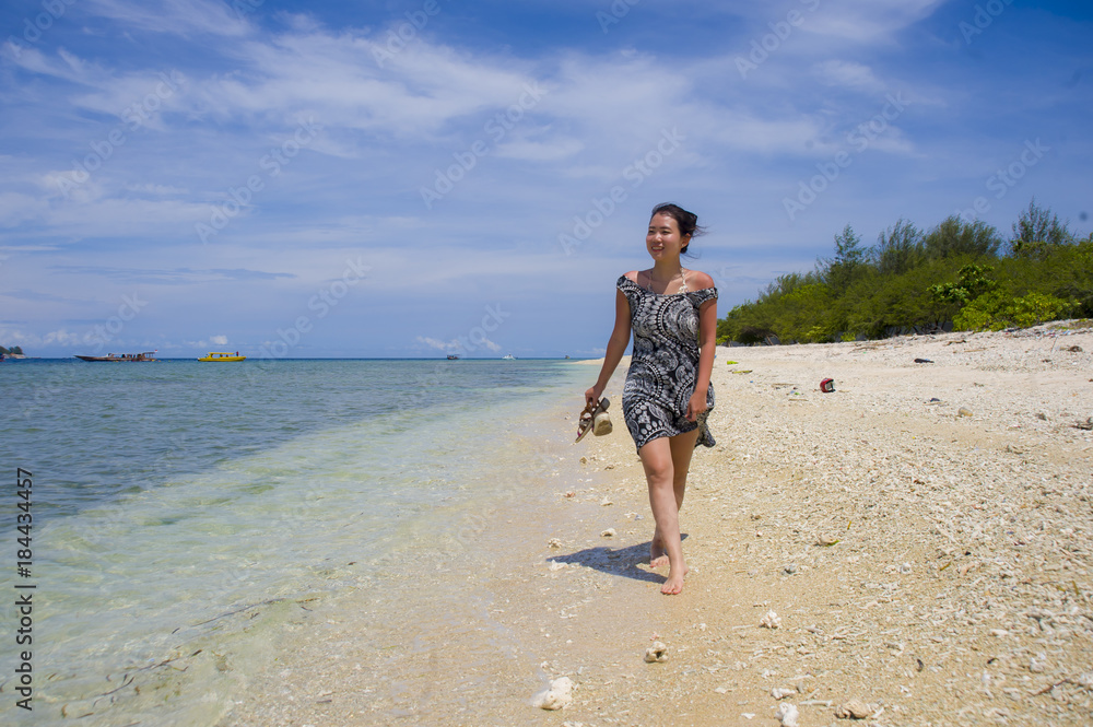 happy Asian Chinese woman in Summer dress walking on beautiful Thailand island beach under a blue sky in holiday