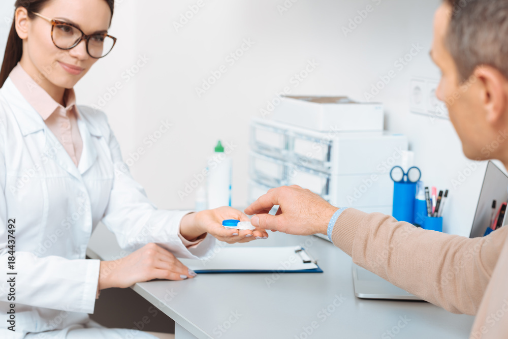 partial view of doctor showing contact lens to patient in clinic partial view of doctor showing contact lens to patient in clinic