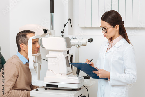 side view of patient getting eye examination in slit lamp in clinic photo