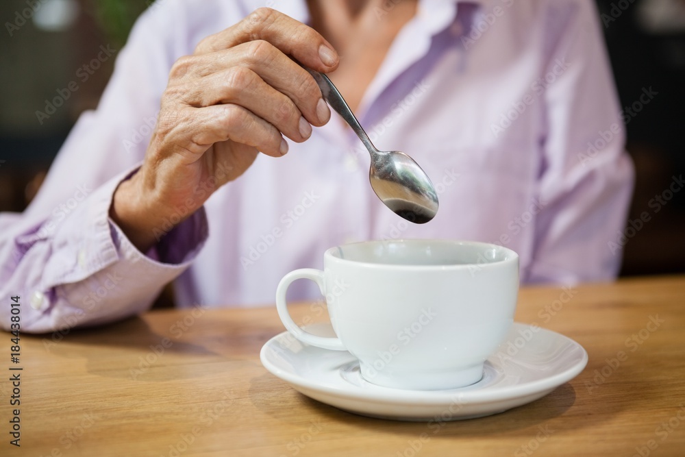 Woman stirring coffee while sitting at table in cafe Woman stirring coffee while sitting at table in cafe