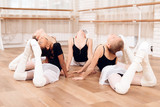 Young ballerinas perform various choreographic exercises lying on the floor.