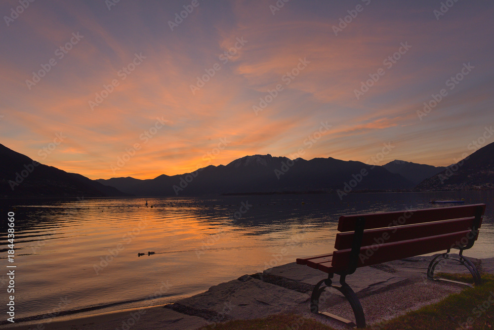 Panchina al molo durante un tramonto serale con cielo colorato di blu, rosa e giallo