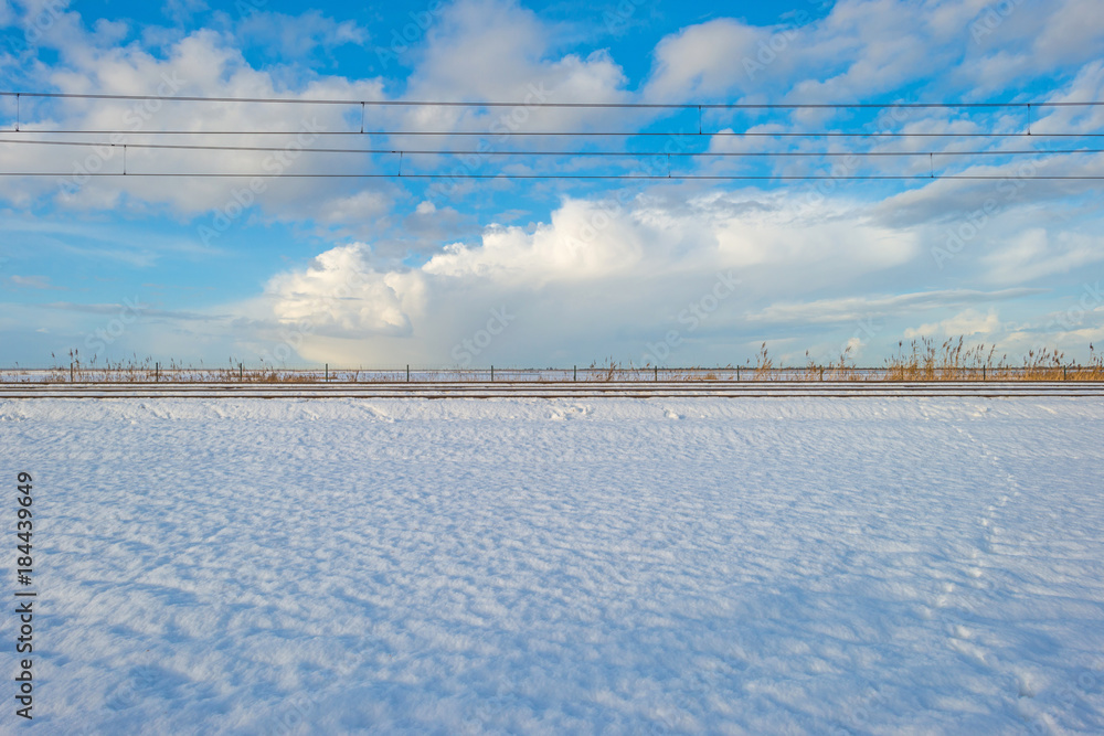 Railway through a snowy field in sunlight in winter Railway through a snowy field in sunlight in winter