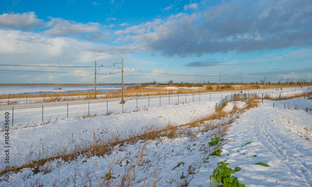 Railway through a snowy field in sunlight in winter Railway through a snowy field in sunlight in winter