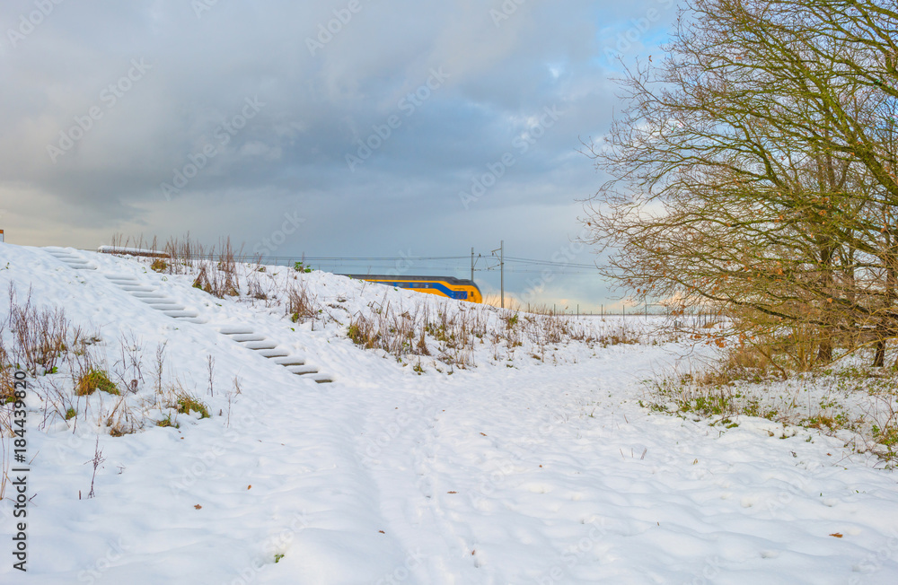 Railway through a snowy field in sunlight in winter Railway through a snowy field in sunlight in winter