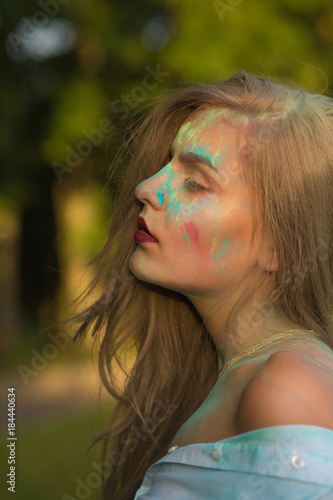Sensual young woman with naked shoulders covered Holi colorful paint