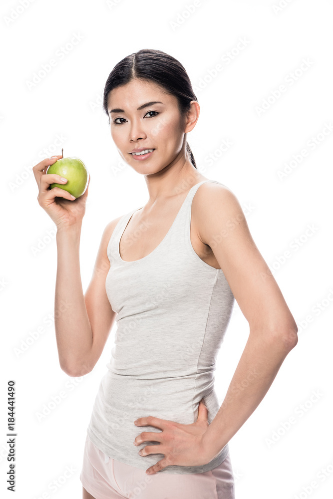 Happy Asian young woman looking at camera, while holding a green apple against white background Happy Asian young woman looking at camera, while holding a green apple against white background