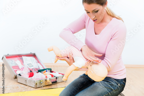 Woman in first aid course practicing revival of infant on baby doll
