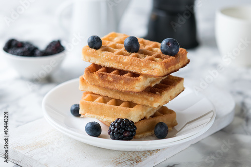 Waffles on a white plate decorated with blueberries with marbled background. copy space photo