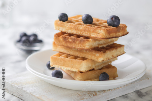 Waffles on a white plate decorated with blueberries with marbled background. copy space photo