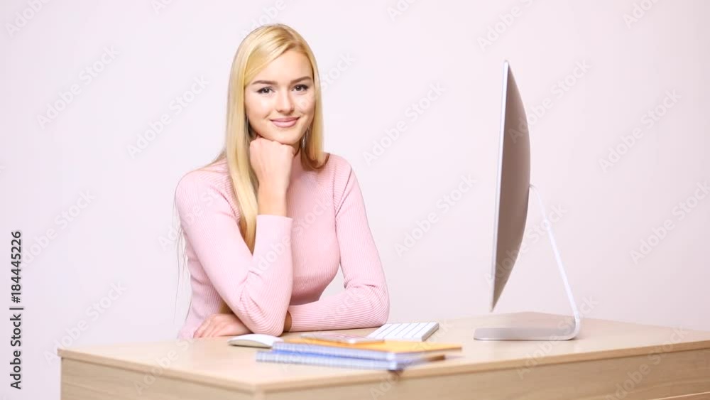Woman secretary works, using computer sitting at table in company on white wall. Female in glasses looks at papers carefully and types text, tapping with fingers on keyboard. Woman secretary works, using computer sitting at table in company on white wall. Female in glasses looks at papers carefully and types text, tapping with fingers on keyboard.