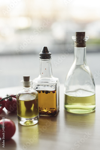 close up view of various types of oil in bottles and fresh cherry tomatoes