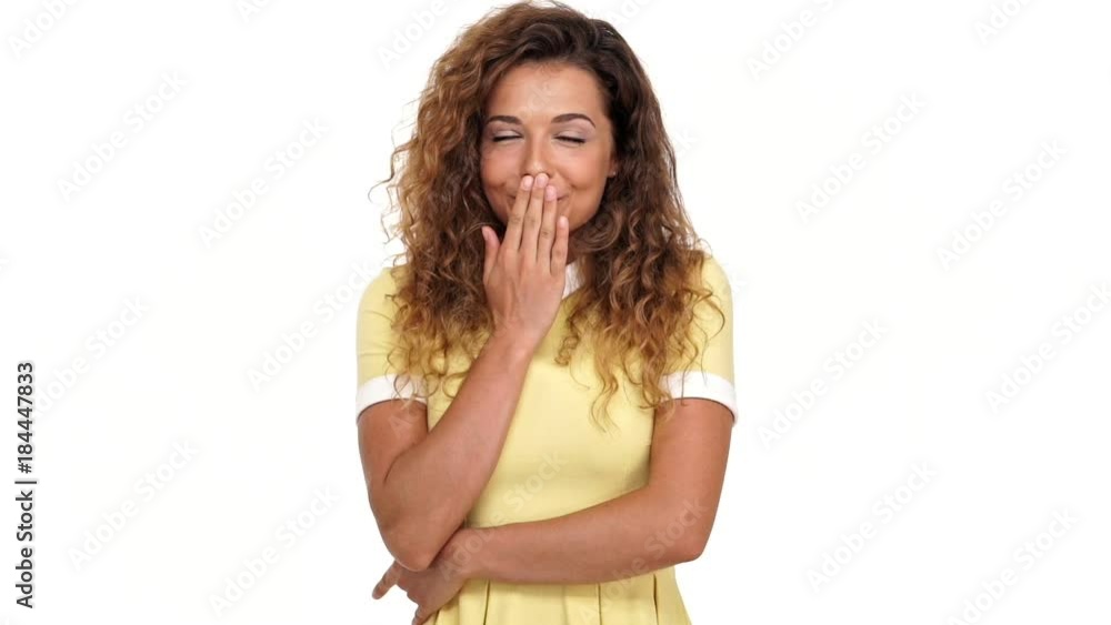 Happy sly curly woman in dress covering her mouth and looking at the camera over white background
Happy sly curly woman in dress covering her mouth and looking at the camera over white background