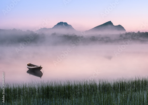 Very peaceful summer night with wooden boat and fog in Lofoten, Norway