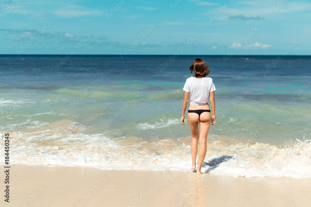 Beautiful young woman in bikini posing on the beach of a tropical island of Bali, Indonesia. Beautiful young woman in bikini posing on the beach of a tropical island of Bali, Indonesia.