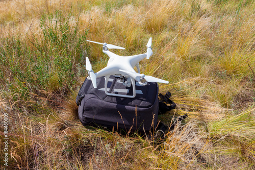 White drone on grass background. Close up of quadrocopter with bag outdoors. photo