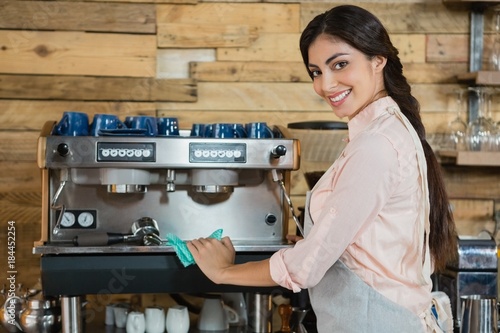 Portrait of waitress cleaning coffeemaker machine photo