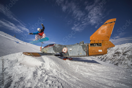 Snowboarding jump over plane in snowpark winter mountains
