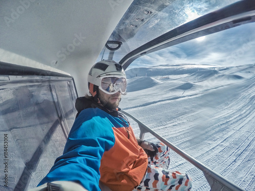 Snowboarder at elevator in Alps mountains sunny day photo