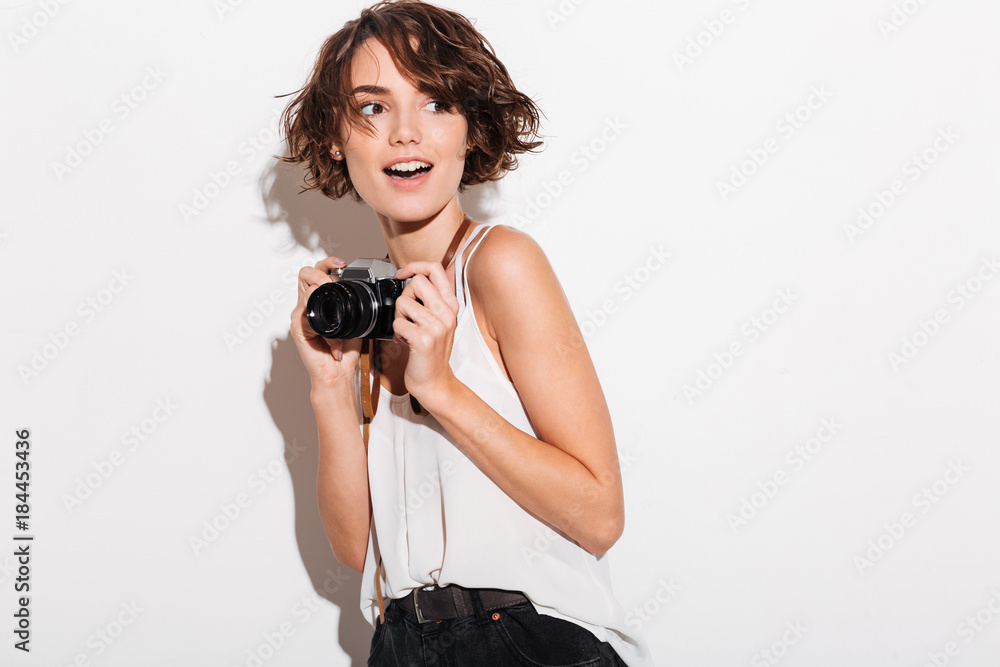 Happy woman wearing sunglasses holding retro camera.