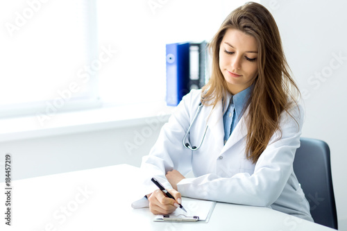 Doctor makes notes in a notebook sitting in the office