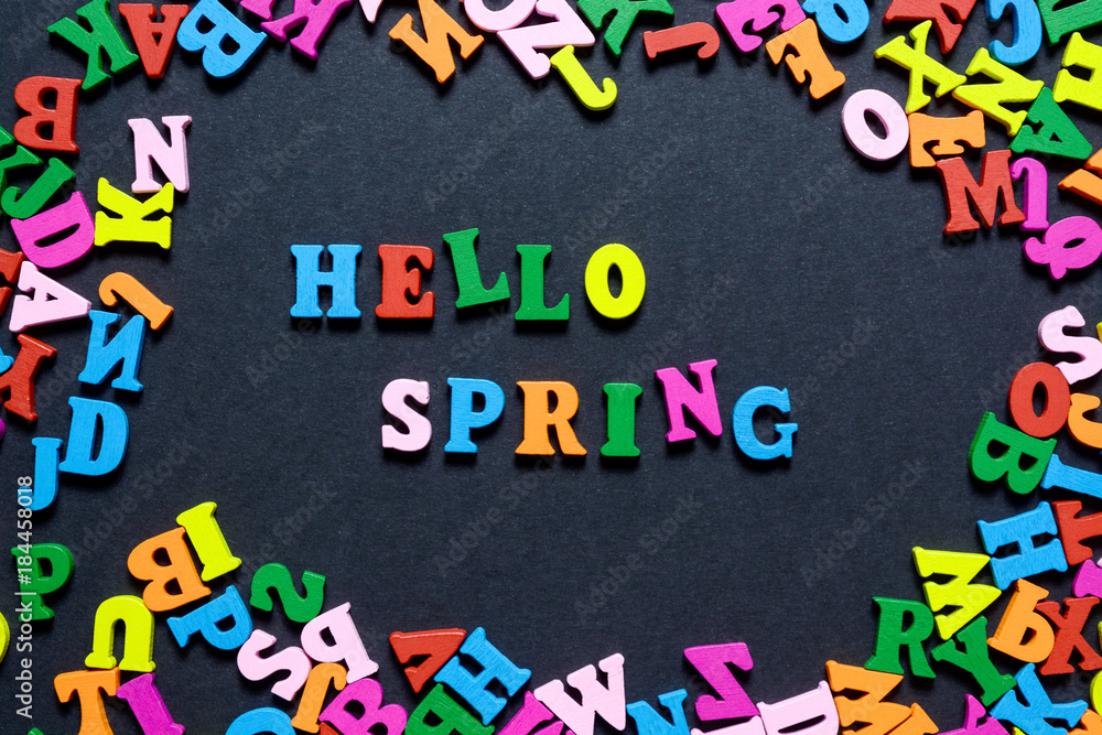 concept design - the word HELLO on SPRING from multi-colored wooden letters on a black background, creative idea. concept design - the word HELLO on SPRING from multi-colored wooden letters on a black background, creative idea.