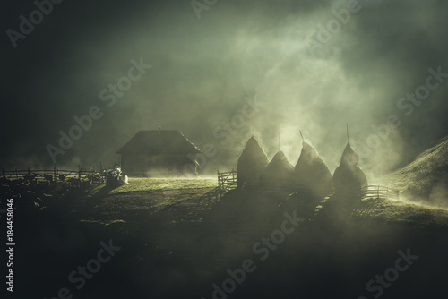 Foggy morning in the Carpathian mountains. Farmi house with haystacks photo