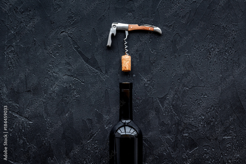 Open the wine. Corkscrew near bottle on black background top view copyspace Open the wine. Corkscrew near bottle on black background top view copyspace
